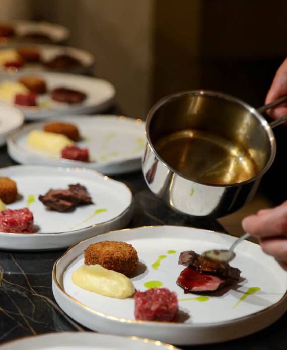 Chef privato che impiatta con cura un secondo di carne durante un servizio a domicilio a bergamo e milano